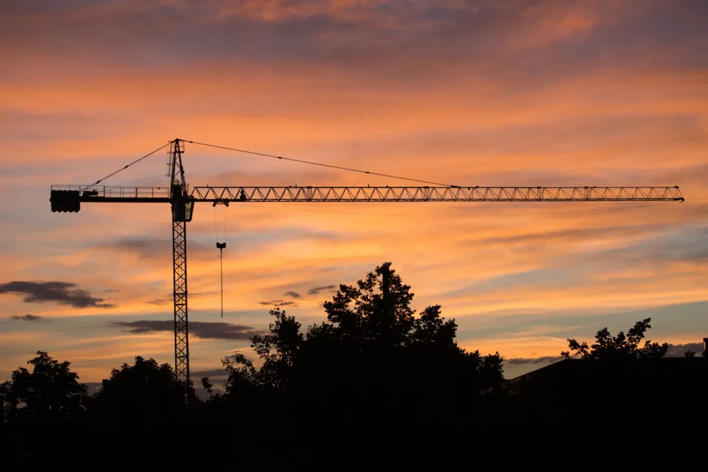 Guindaste de obra em silhueta ao pôr do sol