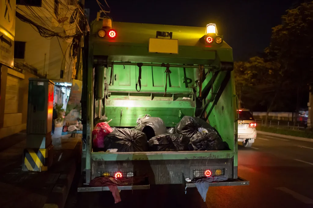 Caminhão de coleta de lixo à noite